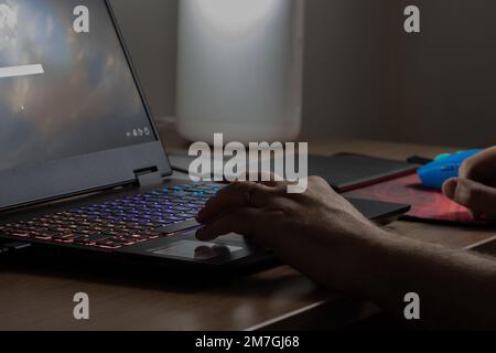 Caucasian man working in front of the notebook with gamer lights on. Stock Photo