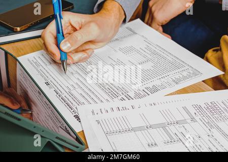 Close-up of man's hands filling US individual tax forms. Accounting, tax season Stock Photo