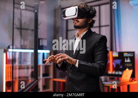 Business man in VR glasses standing at office room and gesturing with hands. Young male company worker having briefing with modern technology. Concept of people and augmented reality. Stock Photo