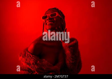 Attractive black ethnic woman with braids with red led lights, trap dancer wearing sunglasses Stock Photo