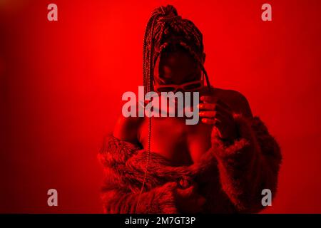 Attractive black ethnic woman with braids with red led lights, trap dancer wearing sunglasses Stock Photo