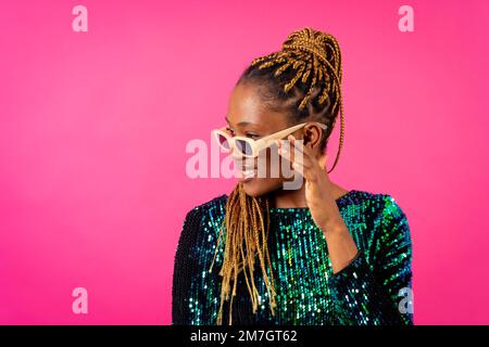 African young woman with party braids on a pink background, studio portrait with glasses Stock Photo