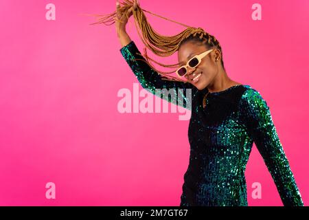 African young woman with party braids on a pink background, studio portrait having fun Stock Photo