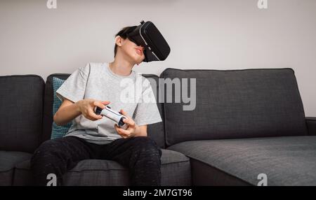 Boy having fun playing simulation games, using virtual reality headset and controller. Children and modern technology concept. Stock Photo