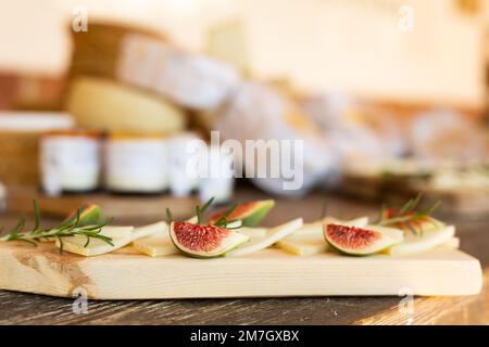 Various types of yellow cheese and fruits on cutting board served on rustic wooden table. French tasting party or holiday scenery Stock Photo