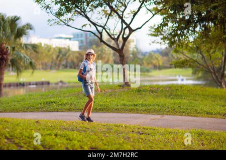 Kids play outdoor and explore nature. Children playing in sunny park. Kids walk and run in beautiful city park. Boy running on warm summer day. Stock Photo