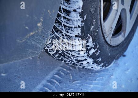 Driving car with winter tire wheel on snow road