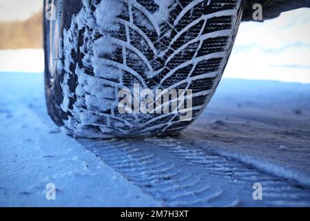 Driving car with winter tire wheel on snow road Stock Photo