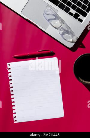 flat lay composition of empty notebook, coffee, computer and glasses on magenta background  Stock Photo