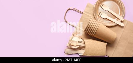 Eco tableware with paper bag on color background with space for text Stock Photo
