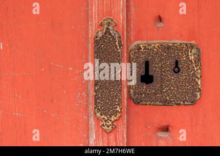 Closeup of rusted antique keyhole and lock on red wooden door Stock Photo