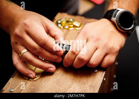 Hands open the combination lock of old wooden chest, close-up Stock Photo
