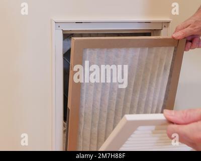 HVAC service technician replacing dirty indoor air filter in residential heating and air conditioning system. Home air duct ventilation system mainten Stock Photo