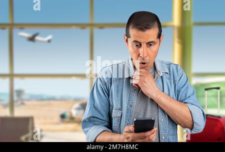 Handsome man using smartphone standing at airport serious face thinking about question very confused idea images Stock Photo