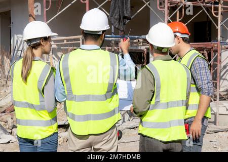 Team group of contractor and architect with foreman explaining about scheme building site for planning project to worker and looking blueprint, constr Stock Photo