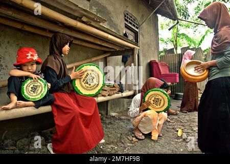 A group of rural children playing rebana, as they are training themselves for an Islamic music performance in Buni, Bekasi , West Java, Indonesia. Stock Photo