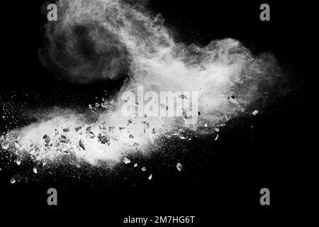 White powder with small stones on black background. Small granite rock stone fly on dust against dark background. Stock Photo