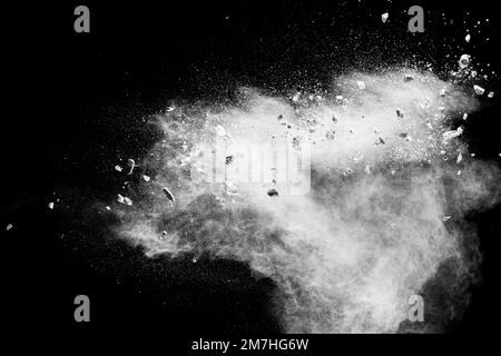 White powder with small stones on black background. Small granite rock stone fly on dust against dark background. Stock Photo