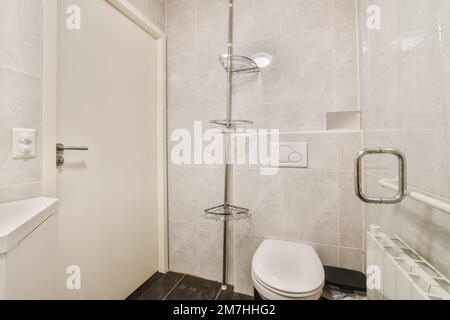 a bathroom with a toilet, sink and shower stall in the corner next to the wall is white marble tiles Stock Photo