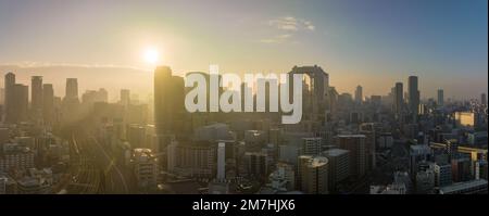 Bright sun rays through haze over downtown Osaka skyline in early morning Stock Photo