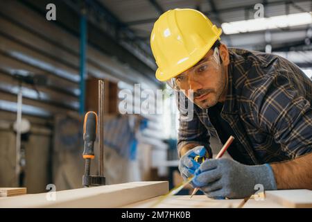 Carpenter man wear gloves during working using tape measure and pencil to make marks piece of wood Stock Photo