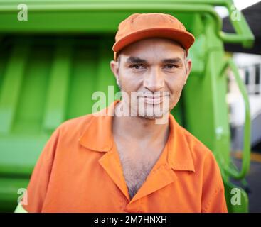 Garbage collection day. Cropped portrait of a garbage collection worker standing by a garbage truck. Stock Photo