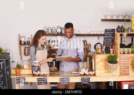 Small business admin just got smarter. young baristas using a digital tablet in a cafe. Stock Photo