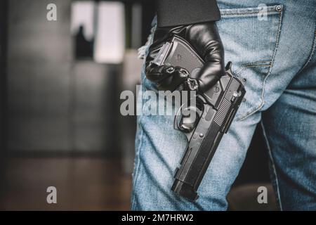 robber in a black glove holds a gun in his hand. weapon for your self defense. a man takes a gun out of his pocket, the concept of self-defense or sup Stock Photo