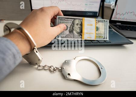 Handcuffs and dollar banknotes on a laptop keyboard. Online crime concept. Stock Photo