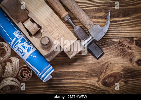 Blue construction plan shaving plane claw hammer chisel wooden studs shavings on wood board. Stock Photo