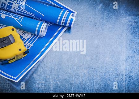 Blue construction plans measuring tape on metallic background horizontal view. Stock Photo