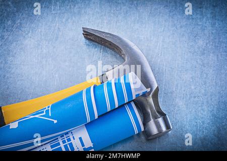 Blue rolled blueprints claw hammer on metallic background construction concept. Stock Photo