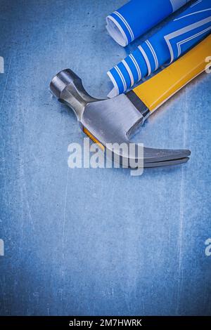 Blue rolled construction plans claw hammer on metallic background. Stock Photo