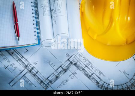 Building helmet checked notebook pen blueprints on construction plan. Stock Photo
