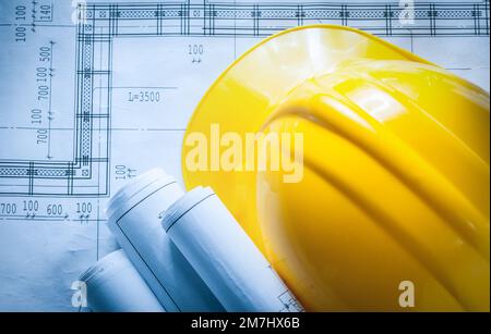 Building helmet rolled construction plans on blueprint. Stock Photo
