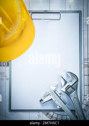 Clipboard building helmet adjustable spanner slide caliper on blueprint. Stock Photo