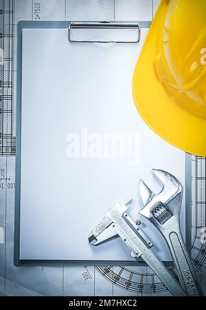 Clipboard building helmet adjustable spanner vernier caliper on blueprint. Stock Photo