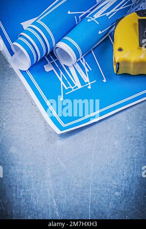 Composition of blue blueprints measuring tape on scratched metallic background. Stock Photo