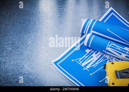 Composition of blue construction plans measuring tape on metallic background. Stock Photo