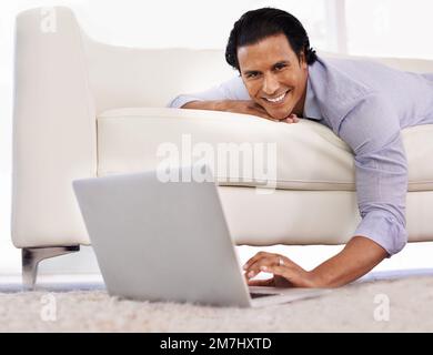 Technology at home. A handsome young man using his laptop at home. Stock Photo