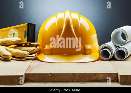 construction composition yellow helmet level gloves rolled blueprints on wood Stock Photo