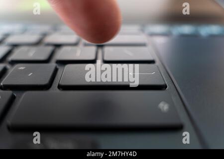 Finger pushing the button of keyboard. Click on the black ultrabook key Stock Photo
