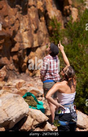 To scale a mountain. Two rock climbers deciding on which route to take up the mountainside. Stock Photo