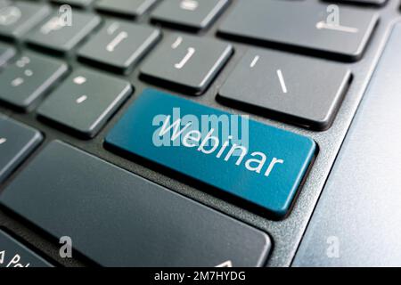 Keyboard with blue key Enter and word Webinar button modern pc text communication board. Color button on the keyboard of modern ultrabook. caption on Stock Photo