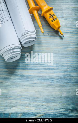 Electric tester rolled engineering drawings on wooden board electricity concept. Stock Photo