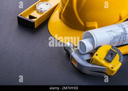 horizontal version level helmet hammer rolled blueprints tapeline on black background Stock Photo