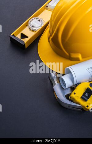 level helmet hammer rolled blueprints tapeline on black background Stock Photo