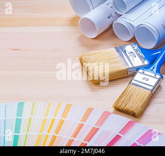 paint brushes and blueprints color palette on wooden board. Stock Photo