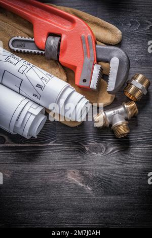 Pipe wrench brass plumbing fittings protective gloves blueprint rolls. Stock Photo