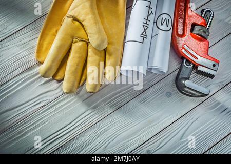 plumbing engineering rolled piping blueprints pipe wrench yellow leather work gloves on vintage white wood background Stock Photo